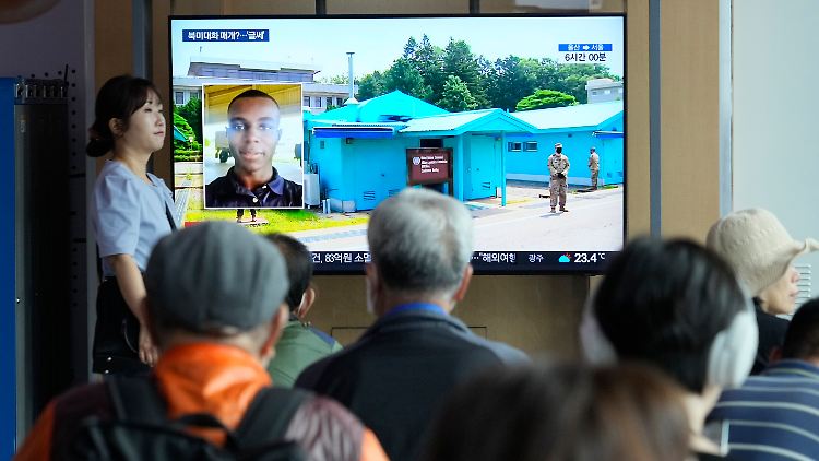 Südkoreaner schauen im Bahnhof von Seoul eine Nachrichtensendung, in der über Travis King berichtet wird.