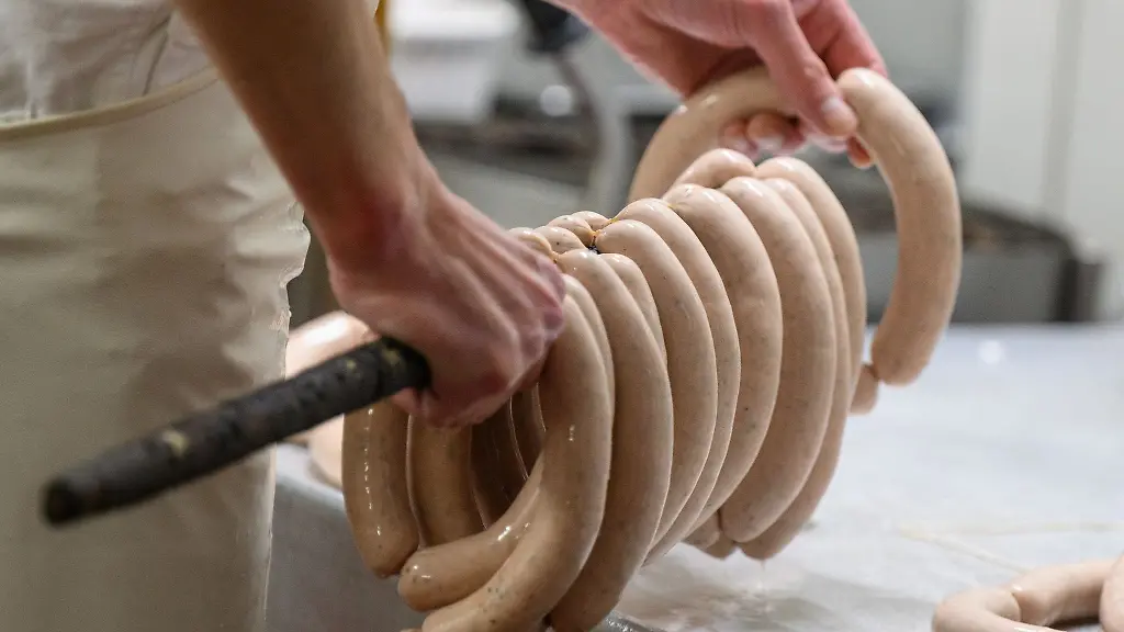 Bratwuerste-werden-in-einer-Fleischerei-vor-dem-Bruehen-auf-eine-Stange-gehaengt