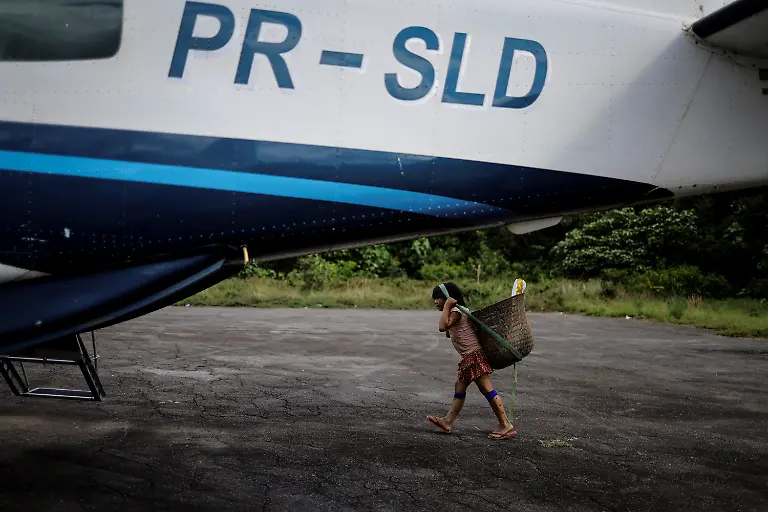 An-Indigenous-child-carries-a-basket-on-their-head-while-crossing-an-official-airstrip
