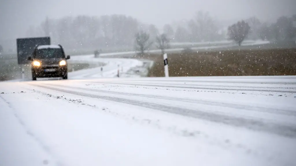 Ein-Auto-faehrt-auf-einer-Strasse-die-mit-Schnee-bedeckt-ist