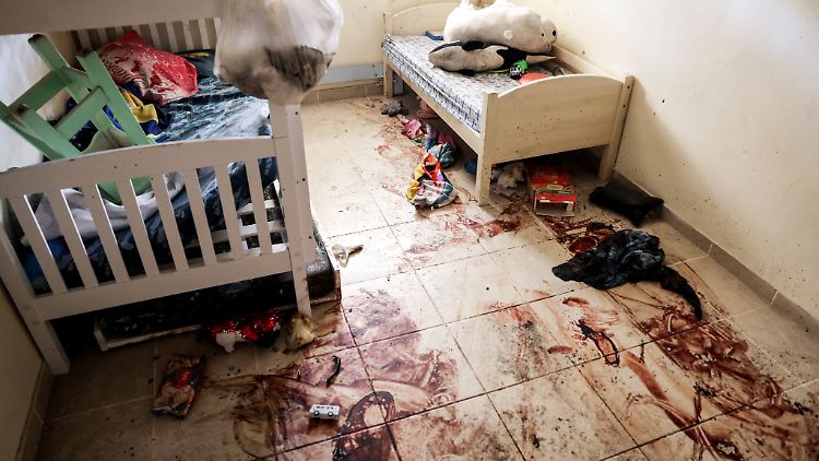 Spielzeug und Kleidung liegen verstreut auf einem blutigen Boden in einem Kinderzimmer im von der Hamas angegriffenen Kibbutz Be'eri.