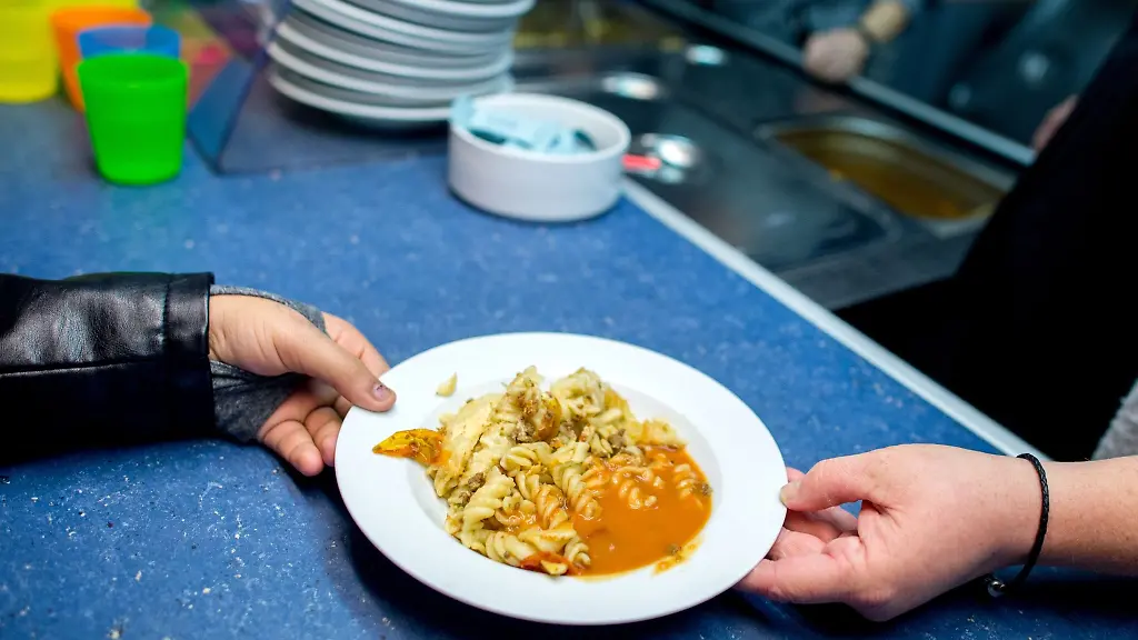 Eine-ehrenamtliche-Mitarbeiterin-verteilt-in-der-Mensa-der-Grundschule-Muehlenberg-in-Hannover-das-Mittagsgericht