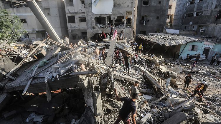 Chan Junis im Gazastreifen am Samstag: Palästinenser stehen auf den Trümmern eines eingestürzten Gebäudes und suchen nach israelischen Angriffen nach Überlebenden und Opfern.