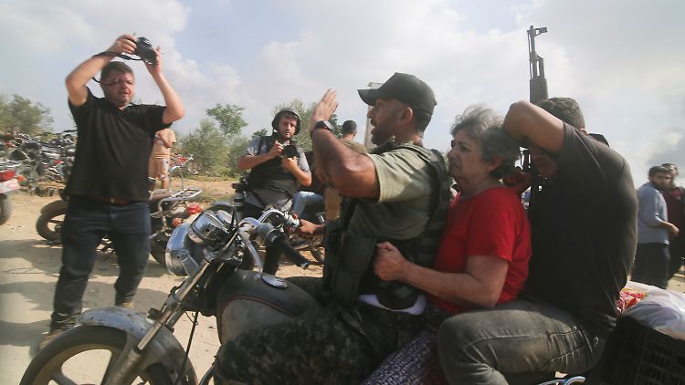 Das Bild der Nachrichtenagentur AP zeigt die Verschleppung einer israelischen Frau am 7. Oktober in den Gazastreifen. Im Hintergrund halten Fotografen mit professioneller Kameraausrüstung die Szene fest.