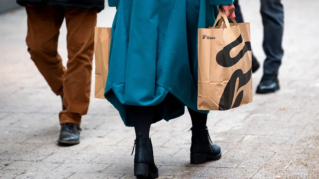 Eine-Frau-mit-Einkaufstueten-in-der-Hand-geht-waehrend-des-verkaufsoffenen-Sonntags-durch-die-Innenstadt