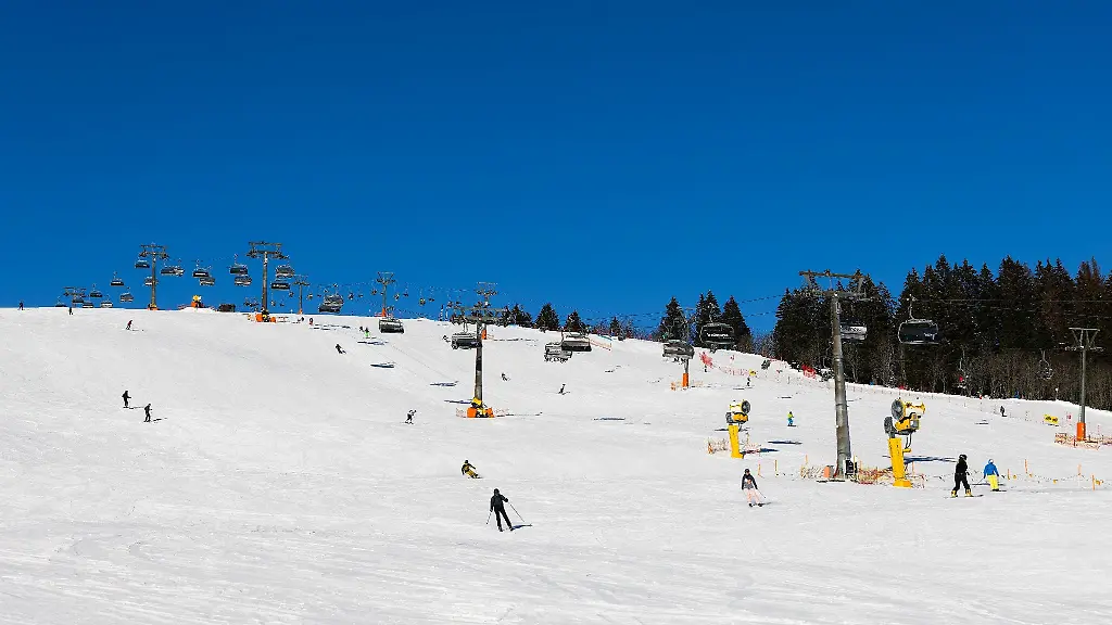 Wintersportler-fahren-unter-den-Kabinen-der-Feldbergbahn-entlang