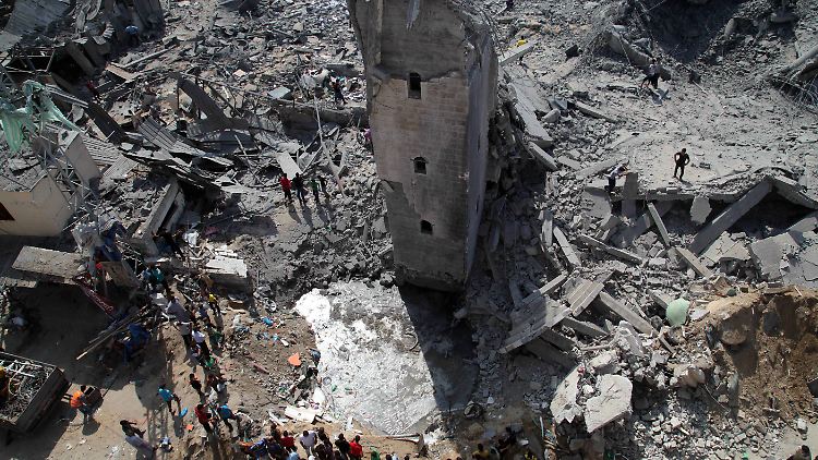 Palästinenser vor einer Ruine des Krieges im Gazastreifen