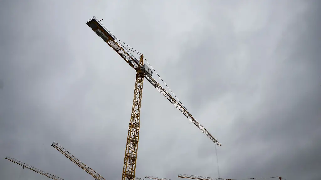 Baukraene-die-auf-einer-Baustelle-stehen-sind-vor-grauem-Himmel-zu-sehen