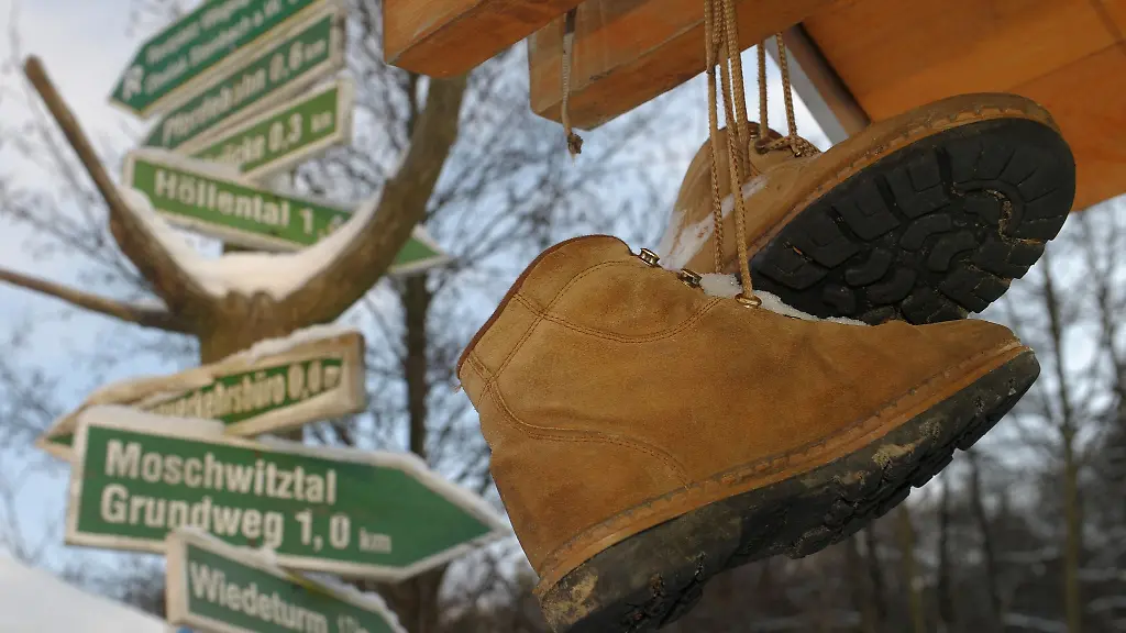 Abgetragene-Wanderschuhe-der-Vorsaison-ueberwintern-an-einem-Rennsteig-Wegweiser