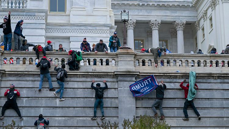 Menschen erklimmen die Westmauer des US-Kapitols.