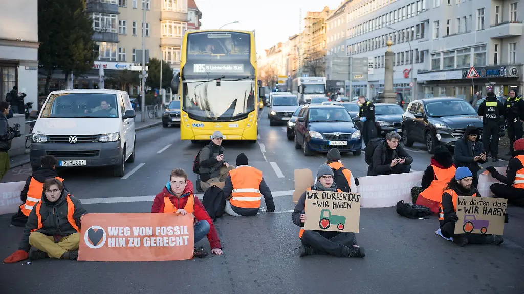 Aktivisten-der-Klimaschutzgruppe-Letzte-Generation-sitzen-bei-einer-Strassenblockade-auf-der-Strasse