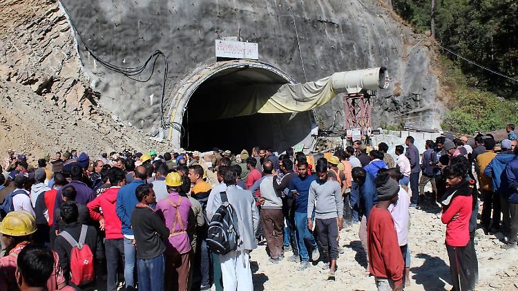 Menschen beobachten Rettungs- und Hilfsmaßnahmen an dem Tunnel.