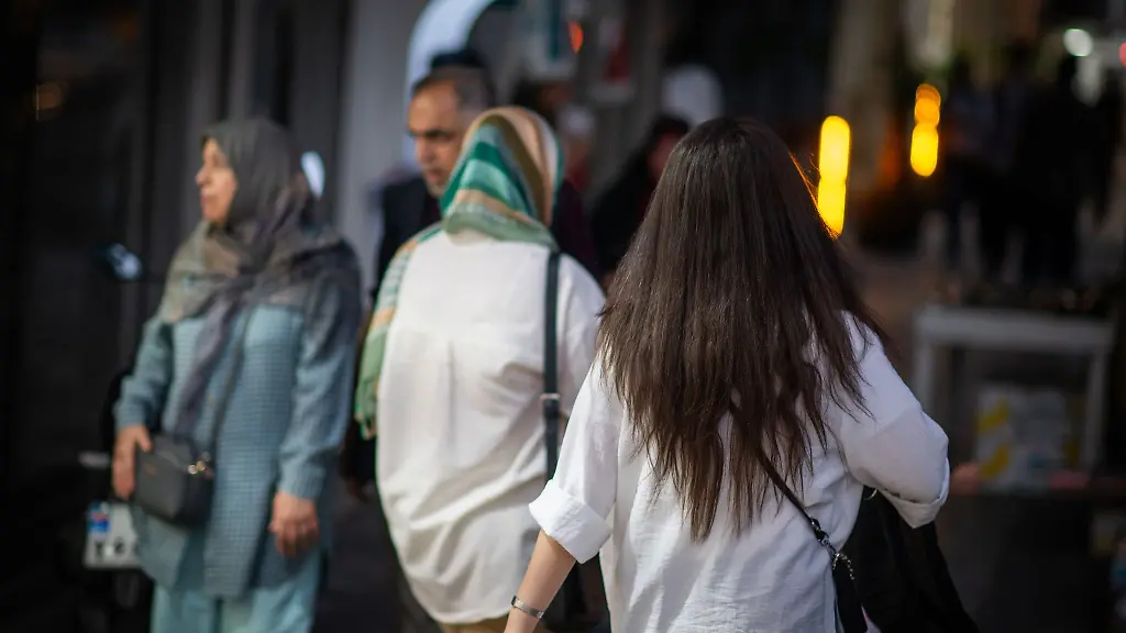 Eine-Frau-laeuft-im-Juli-2023-mit-offenen-Haaren-durch-Teheran-Vor-mehr-als-einem-Jahr-hatte-der-Tod-der-jungen-Kurdin-Jina-Mahsa-Amini-die-bislang-schwersten-Proteste-in-der-Geschichte-der-Islamischen-Republik-ausgeloest-Viele-Frauen-zeigten-sich-daraufhin-ohne-Kopftuch-in-der-Oeffentlichkeit