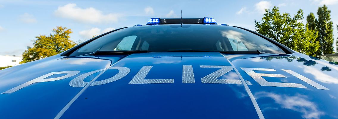 Auf der Motorhaube eines Streifenwagens steht der Schriftzug "Polizei".