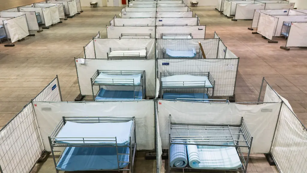 Stockbetten-stehen-zwischen-Zaeunen-in-einer-Notunterkunft-fuer-Asylsuchende