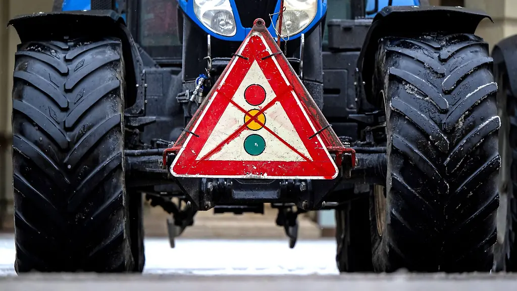Ein-durchgestrichenes-Verkehrsschild-mit-einer-Ampel-haengt-waehrend-einer-Demonstration-von-Landwirten-an-einem-Traktor