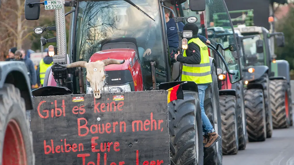Plakats-mit-der-Aufschrift-Gibt-es-keine-Bauern-mehr-bleiben-eure-Teller-leer-ist-bei-einer-Kundgebung-des-Bauernverbandes-gegen-die-Sparplaene-der-Bundesregierung-an-einem-Traktor-angebracht