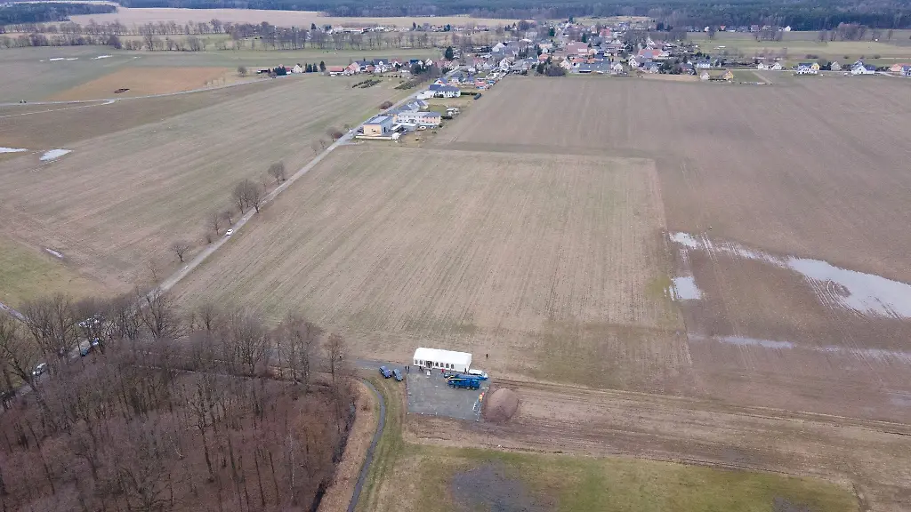 Ein-Bohrfahrzeug-steht-anlaesslich-einer-Probebohrung-fuer-einen-Granitstock-auf-einer-Freiflaeche-neben-einem-Zelt