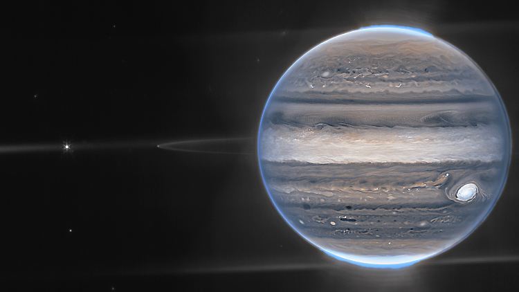 Falschfarbenkompositbild des Jupiter, das vom "James Webb"-Teleskop aufgenommen wurde. Die Ringe des Planeten und einige seiner kleinen Satelliten sind zusammen mit Galaxien im Hintergrund zu sehen. 