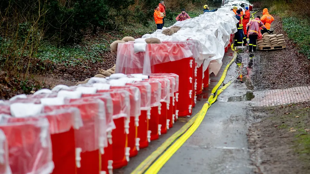 Einsatzkraefte-des-Technischen-Hilfswerks-THW-dichten-ein-mobiles-Deichsystem-bestehend-aus-zahlreichen-grossen-Behaeltern-mit-Wasser-mit-Sandsaecken-ab