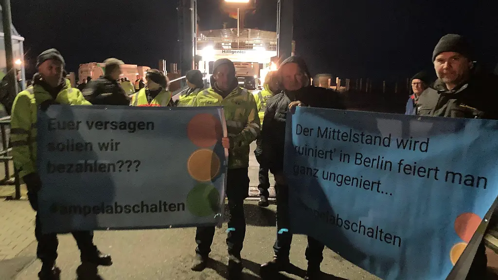Landwirte-stehen-mit-Plakaten-mit-der-Aufschrift-Euer-Versagen-sollen-wir-bezahlen-ampelabschalten-am-Faehranleger