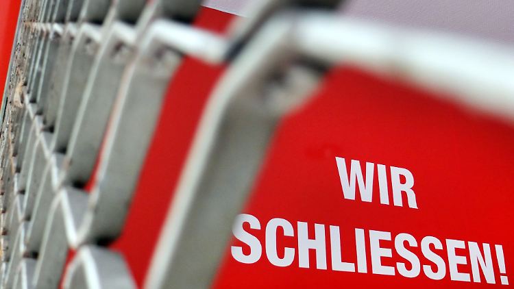 Der Schriftzug "Wir Schliessen" steht hinter einem Rollgitter an einem geschlossenen Geschäft.