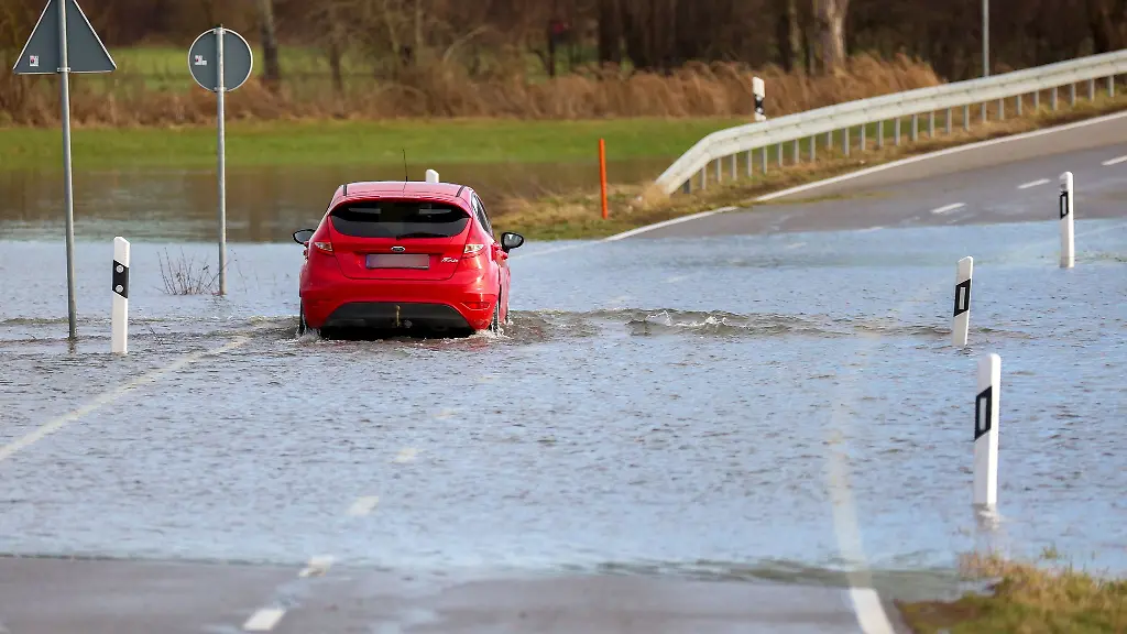 Ein-Auto-faehrt-auf-einer-mit-Hochwasser-ueberfluteten-Strasse-zwischen-Daugendorf-und-Unlingen