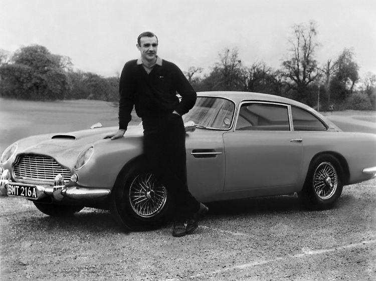 Sean Connery 1964 im James-Bond-Film "Goldfinger" - vor einem Aston Martin DB5.