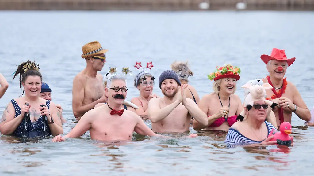 Kostuemierte-Winterschwimmer-des-Vereins-Berliner-Seehunde-nehmen-beim-Neujahrsschwimmen-im-Orankesee-ein-Bad