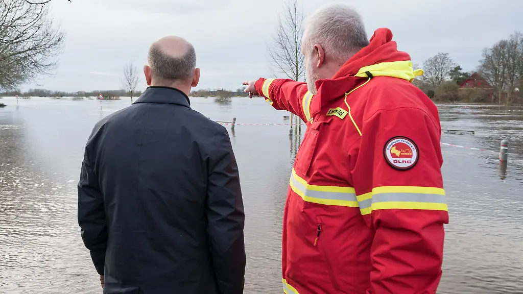 Olaf-Scholz-l-steht-mit-einem-Helfer-der-DLRG-an-einem-ueberfluteten-Gebiet-in-Verden-Aller