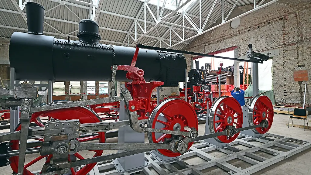 Eine-preussische-T13-Dampflokomotive-wird-mit-dem-Spezialkran-in-eine-Gebaeudeoeffnung-gehoben-wo-schon-weitere-Teile-der-Lok-stehen
