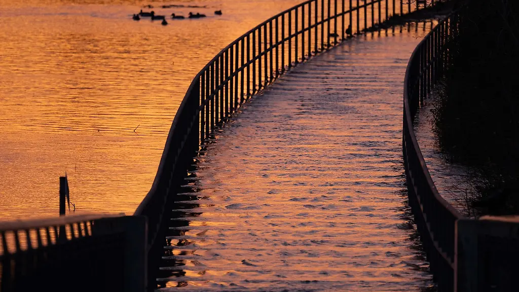 Das-Licht-der-aufgehenden-Sonne-spiegelt-sich-im-Hochwasser-der-Elbe-auf-einem-Radweg
