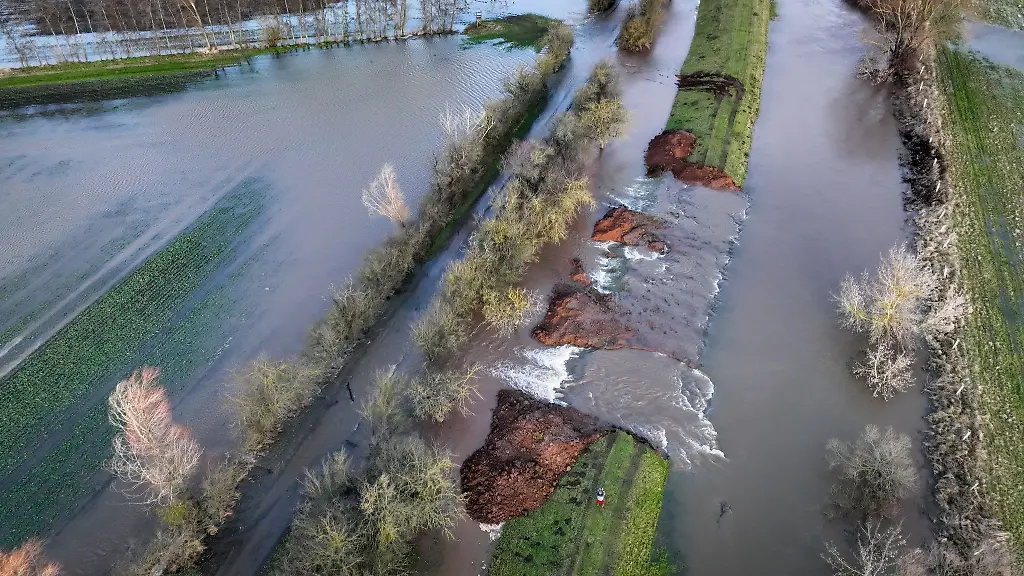 Wassermassen-fliessen-durch-die-Deichoeffnung-am-Fluss-Helme-auf-die-umliegenden-Flaechen