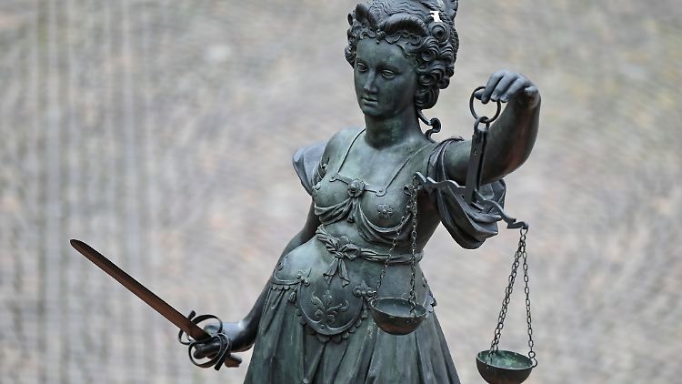 Eine Statue der Justitia hält eine Waage und ein Schwert in der Hand.