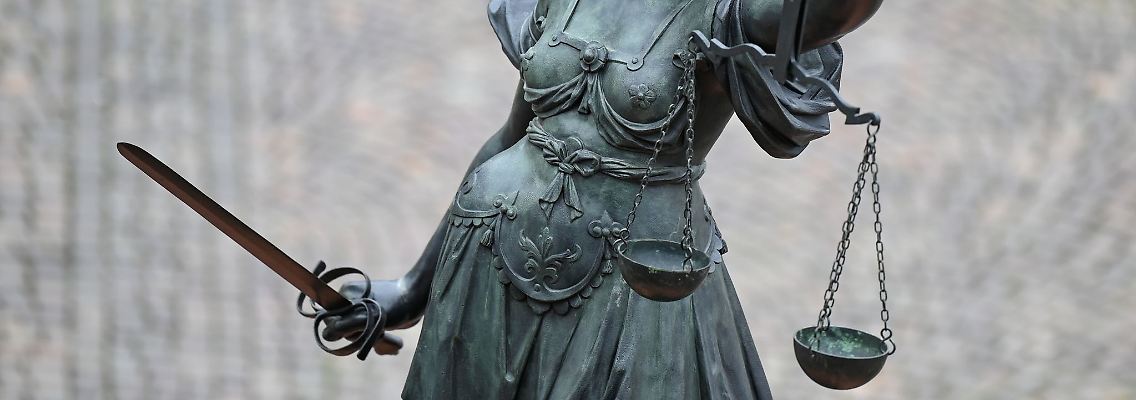 Eine Statue der Justitia hält eine Waage und ein Schwert in der Hand.