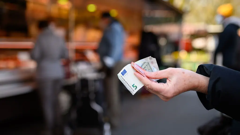 Eine-Frau-haelt-das-Bargeld-fuer-ihren-Einkauf-in-der-Hand-bereit