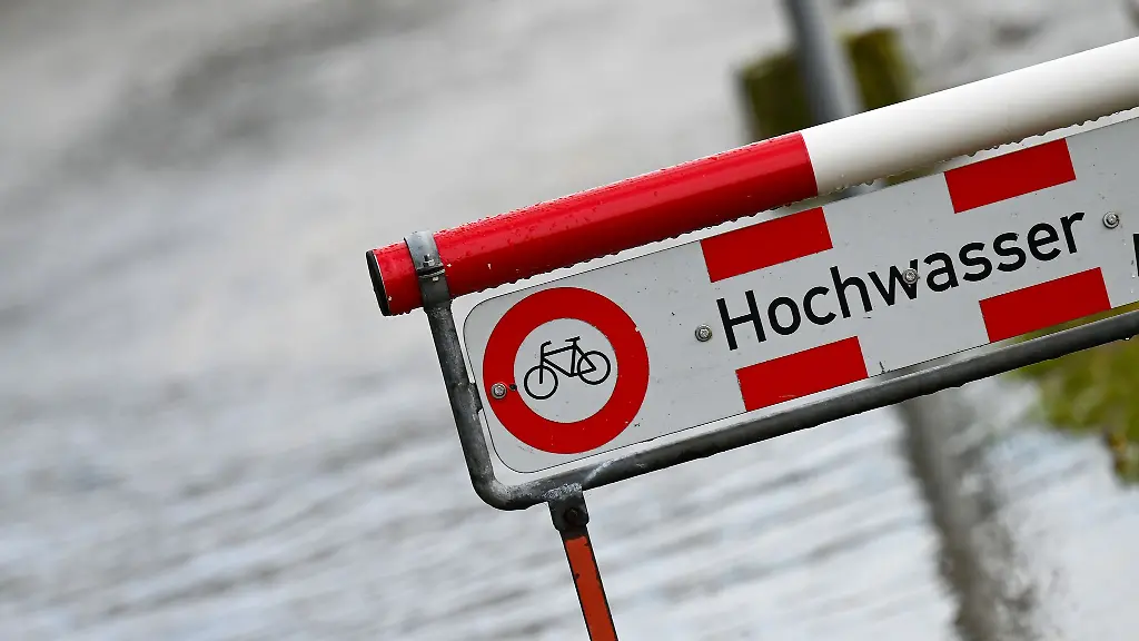 Ein-Schild-mit-der-Aufschrift-Hochwasser-steht-an-einem-Fluss