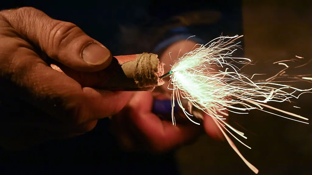 Ein-Mann-zuendet-einen-Boeller-am-Silvesterabend-an
