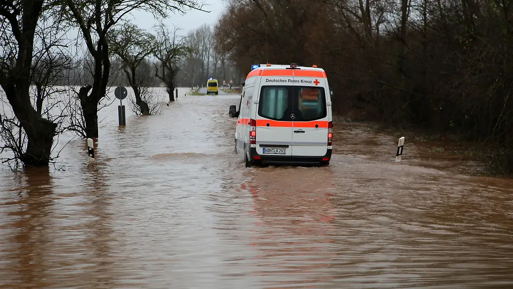 Ein-Krankenwagen-faehrt-ueber-eine-von-Hochwasser-ueberflutete-Strasse-nach-Windehausen