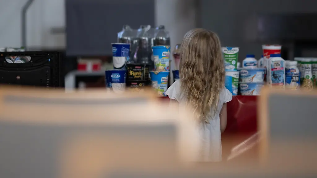 Ein-Kind-schaut-sich-waehrend-der-Ausgabezeit-in-der-Berliner-Tafel-die-Auslage-von-Lebensmitteln-an