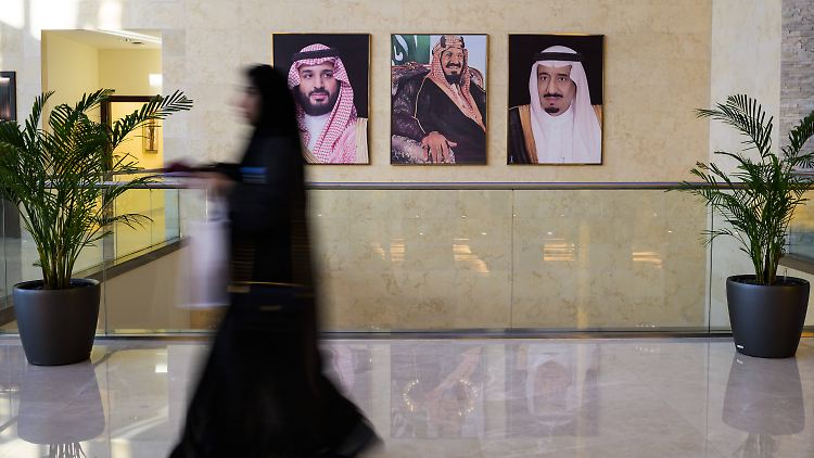Eine Frau passiert in Riad die Porträts des Kronprinzen, des ehemaligen und des aktuellen Königs (v.l.) von Saudi-Arabien.