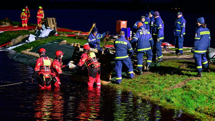 Ehrenamtliche Einsatzkräfte vom THW und der DLRG befestigen im niedersächsischen Hodenhagen einen Deich.