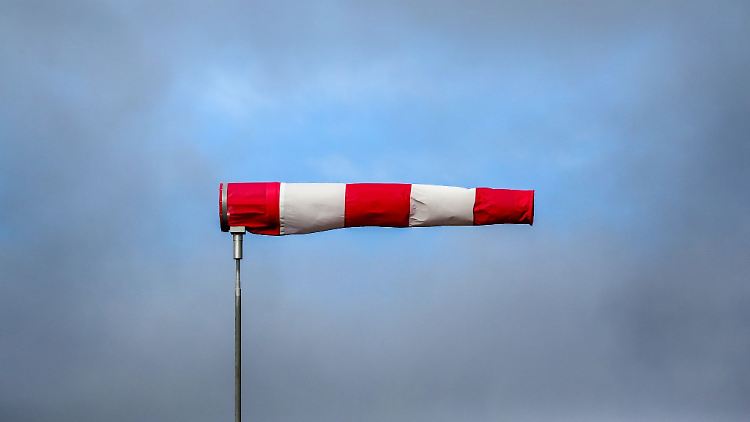 Hinter einem im Sturm stehenden Windsack hat sich eine Wolkenlücke gebildet.