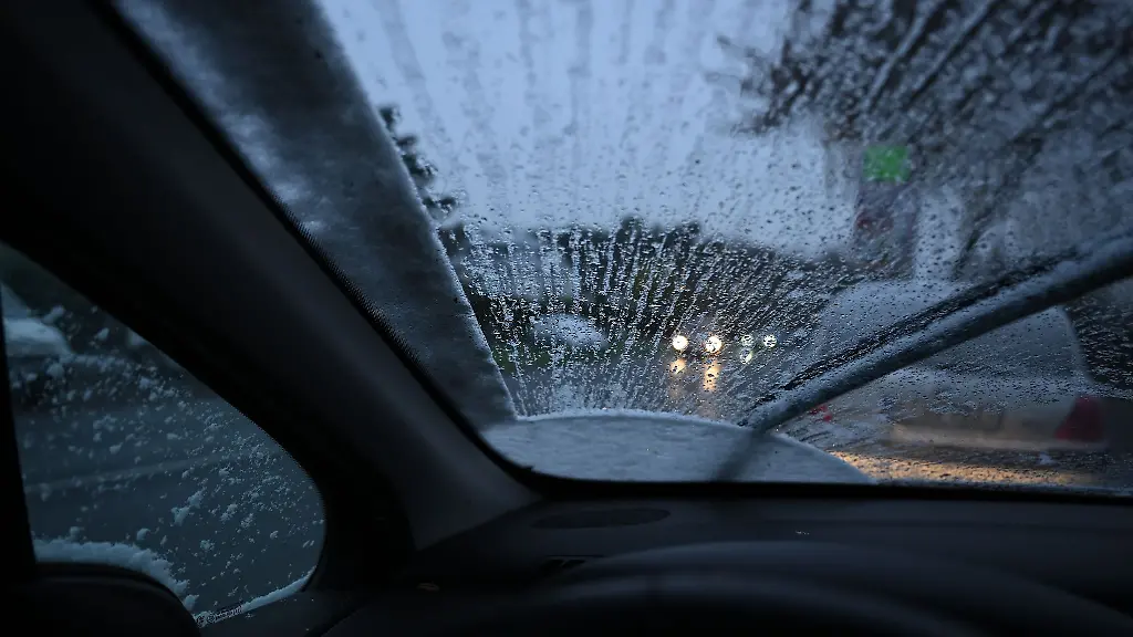 Durch-die-Windschutzscheibe-eines-PKWs-ist-der-Verkehr-im-Schneeregen-zu-sehen