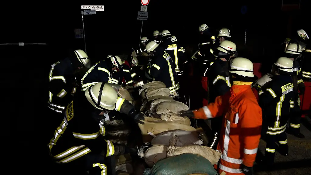 Einsatzkraefte-der-Feuerwehr-sichern-eine-Deichschart-mit-Sandsaecken