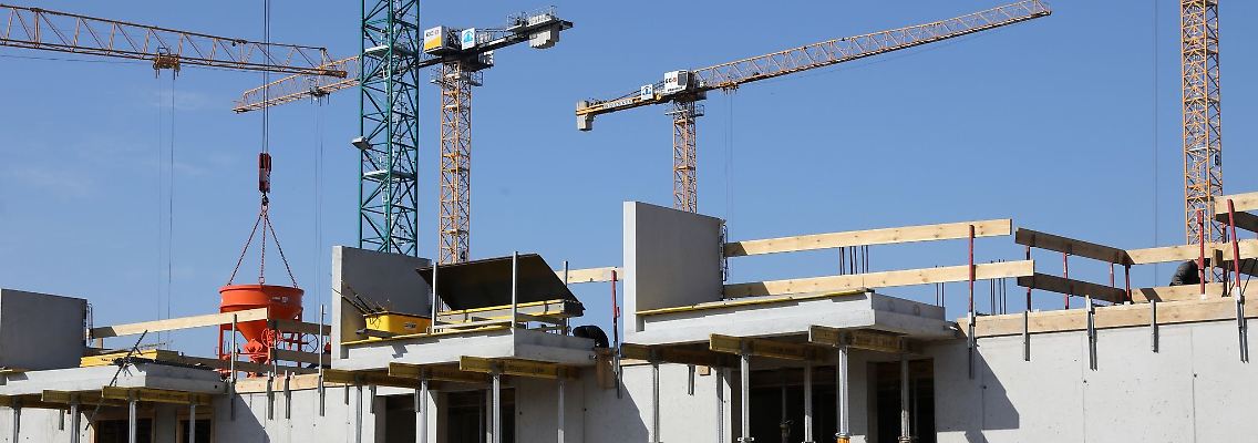 Kräne und Gerüste stehen auf der Baustelle eines Mehrfamilienhauses.