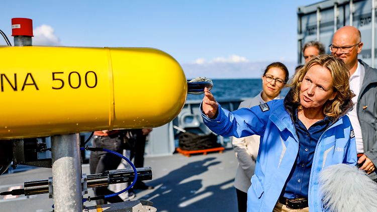 Lemke im Septeber 2023 an Bord eines Marineschiffes vor einem "AUV" (Autonomous Underwater Vehicle), dass zur Kartierung und Suche von Munitionsresten im Wasser eingesetzt wird