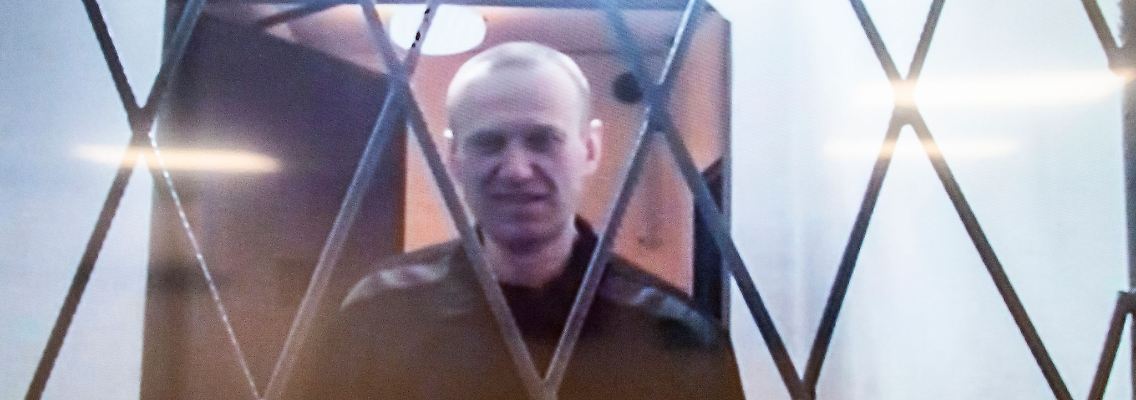 Alexej Nawalny ist auf einem Fernsehbildschirm zu sehen, als er per Video aus einem Gerichtssaal erscheint.