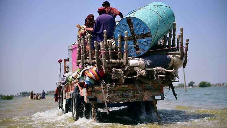 Opfer von Überschwemmungen durch Monsunregen in Pakistan retten sich und ihre Habseligkeiten aus ihrem überfluteten Haus.