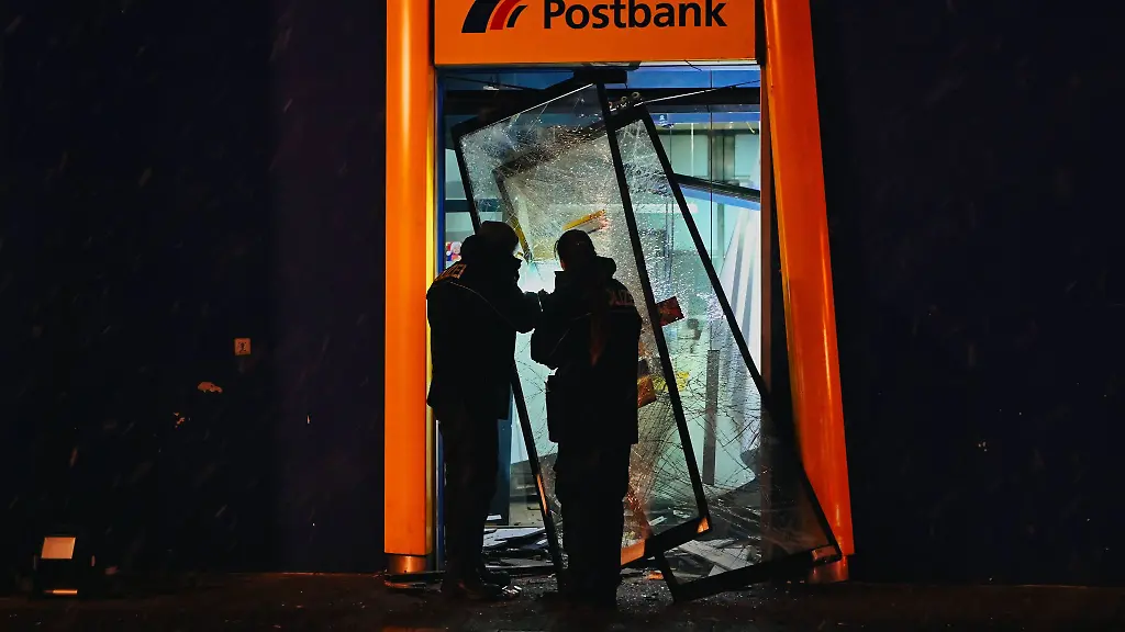 Polizisten-stehen-im-zerstoerten-Eingangsbereich-einer-Bank